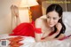 A woman in a red dress laying on a bed.