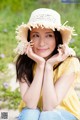 A young woman wearing a straw hat sitting on the ground.