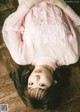 A young girl laying on the floor wearing a pink sweater.