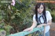 A woman in a school uniform leaning on a fence.