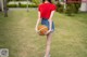 A woman holding a basketball in a grassy field.