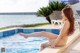 A naked woman sitting on the edge of a swimming pool.