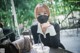 A woman sitting at a table wearing a face mask.