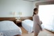 A woman standing in a hotel room next to two beds.