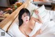 A woman laying on top of a bed covered in white sheets.