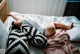 A woman laying on a bed with pillows and a blanket.