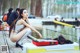 A woman sitting on top of a boat next to a body of water.