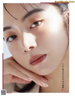 A close up of a woman's face with her hand on her chin.