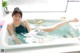 A woman laying in a bathtub with her feet in the water.