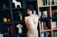 A naked woman standing in front of a bookshelf.