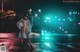 A woman wearing a face mask standing in the middle of a street at night.